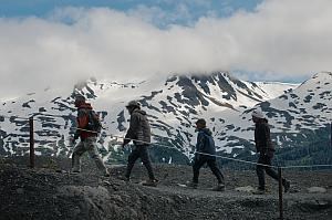 A family hikes against a backdrop of mountains in Kenai Fjords National Park