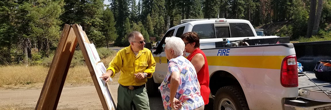 Public Information Officer explains fire activity to two members of the public.