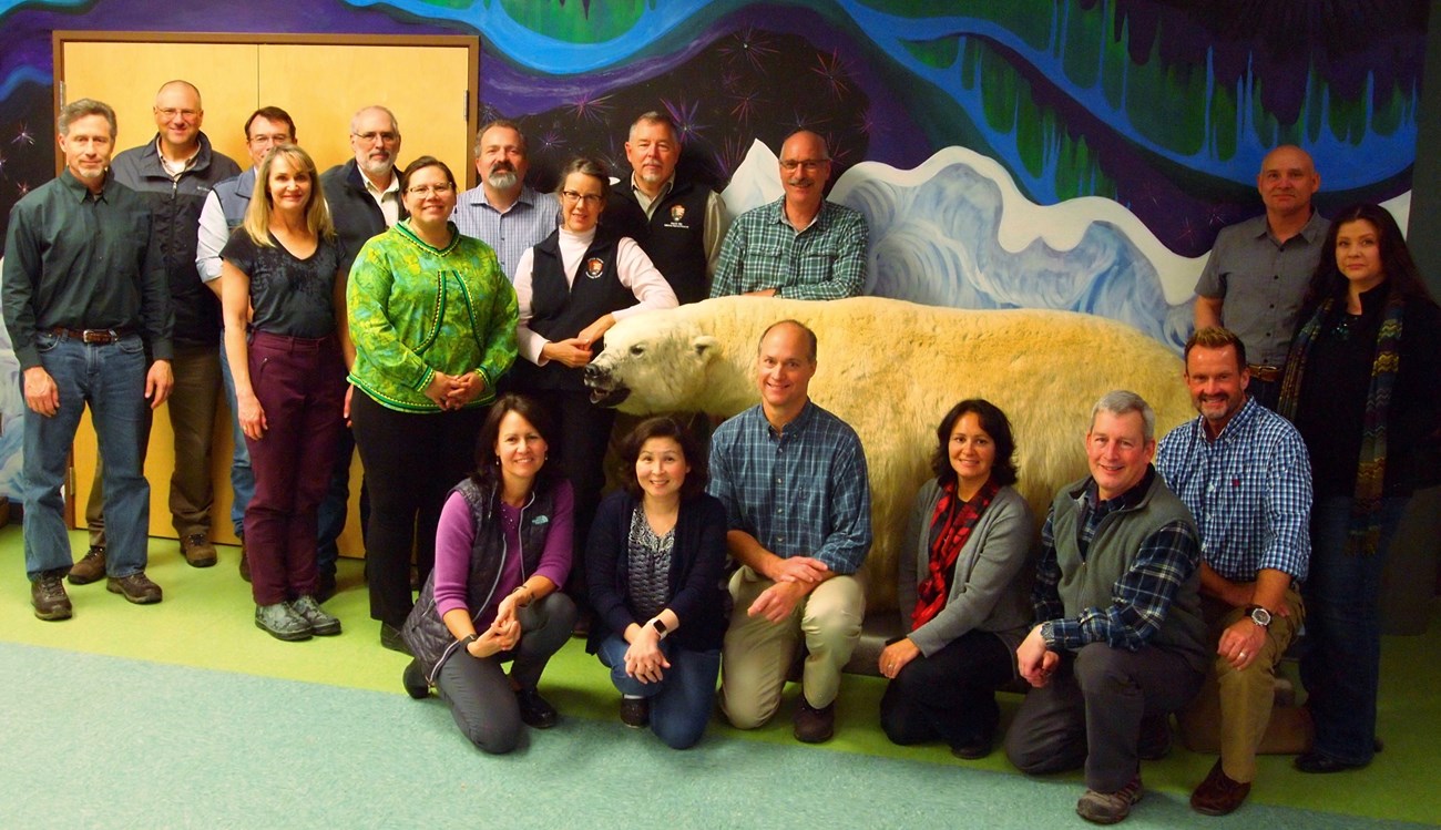 a group of 17 people stand near a colorfully painted wall