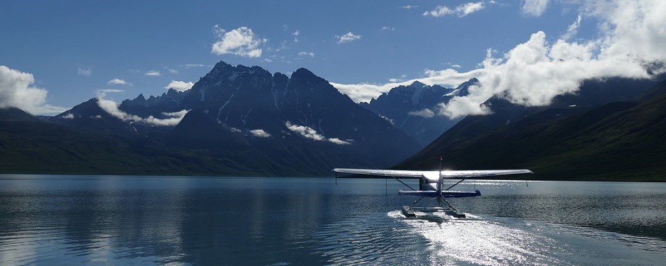 Floatplane on high alpine lake taxis for takeoff.