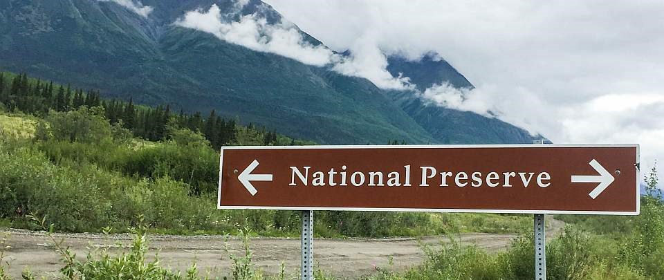 a sign that says national preserve in front of mountains