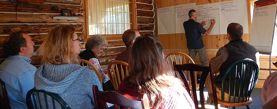 a group of park employees sit while a man writes on poster paper