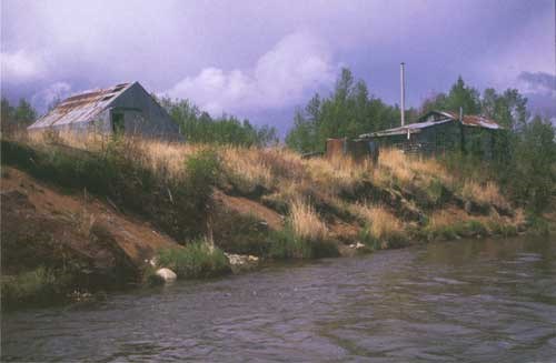 Two metal structures sitting on the bank of a river.