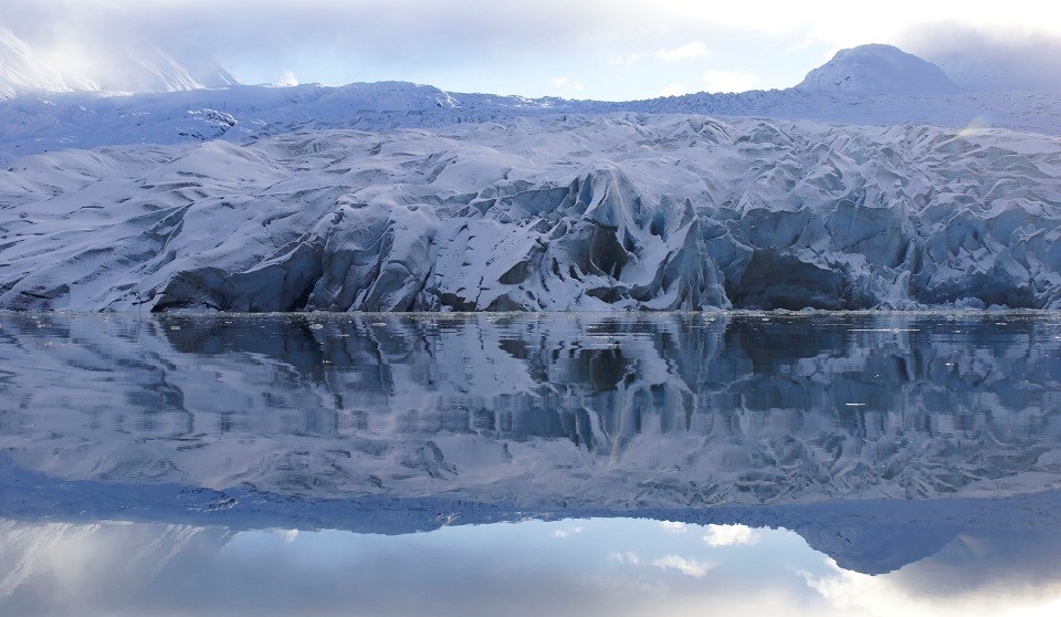 glaciers and mountains reflect in calm water