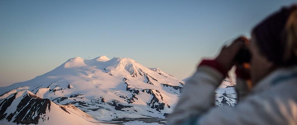 a park visitor looks out over a snow covered volcano