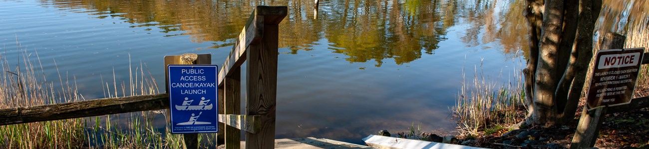 A hand boat launch and small staircase enter the water with a sign directing visitors.