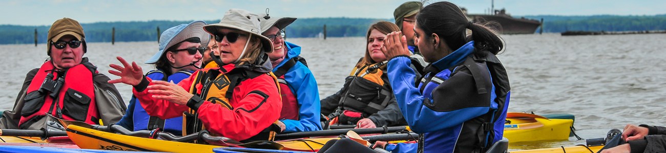 A group of kayakers gather to talk while on the water.