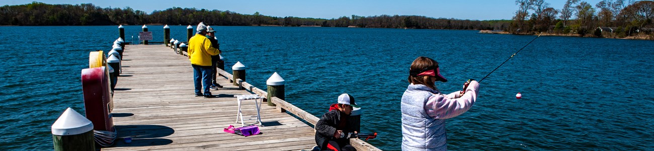 Several people fish from a pier.
