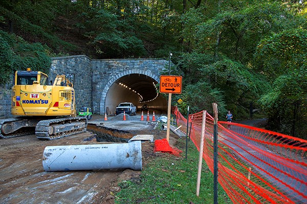 Construction equipment and orange barrels and fencing and a detour sign at the zoo tunnel.