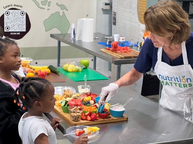 A woman doing a cooking demonstration with two children