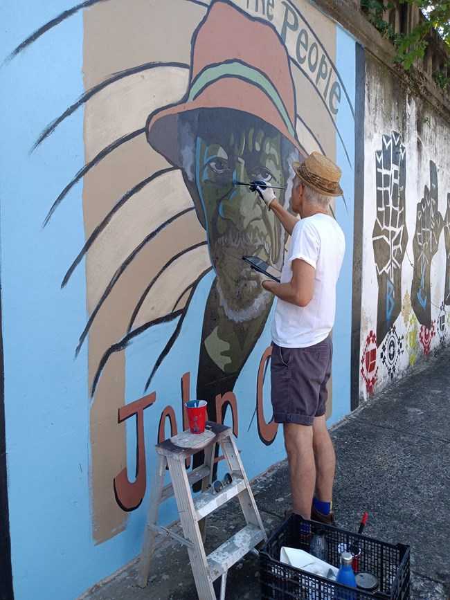 A man painting a mural at Arkansas Peace Week