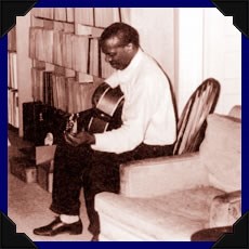 Skip James holding a guitar