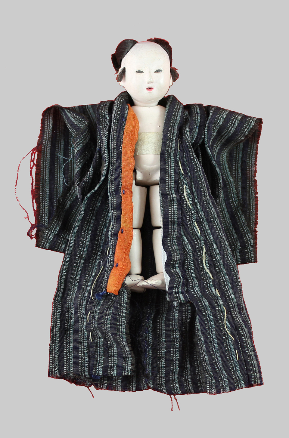 A small 19th century Japanese jointed mitsuori doll wearing a silk striped kimono.