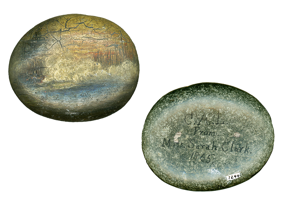 A small smooth stone with a maritime scene painted on it.