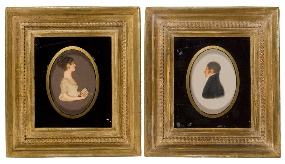 Framed wax portraits of a man and woman in early 19th-century dress.