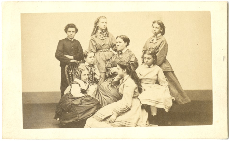 Studio portrait of six girls and one boy group around woman seated in center