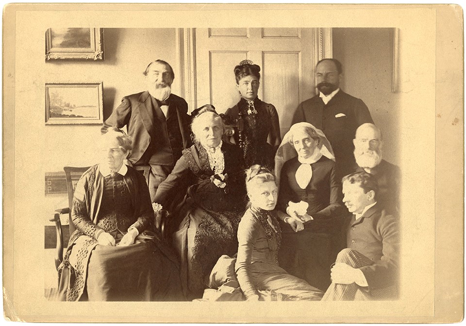 Group portrait of family seated and standing in interior of home