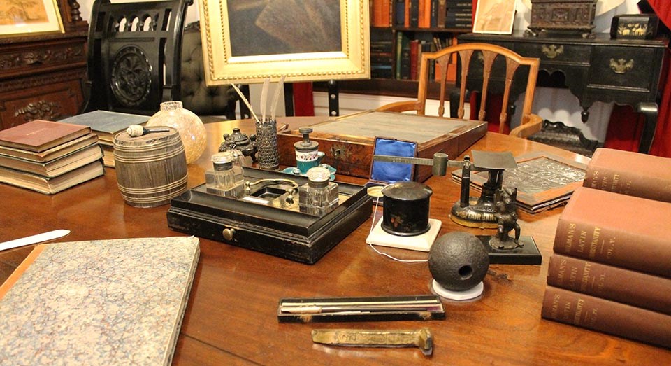 Table with folding desk, writing implements, and piles of books