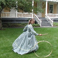 A volunteer in period costume plays a 19th century lawn game. A volunteer in period costume plays a 19th century lawn game.