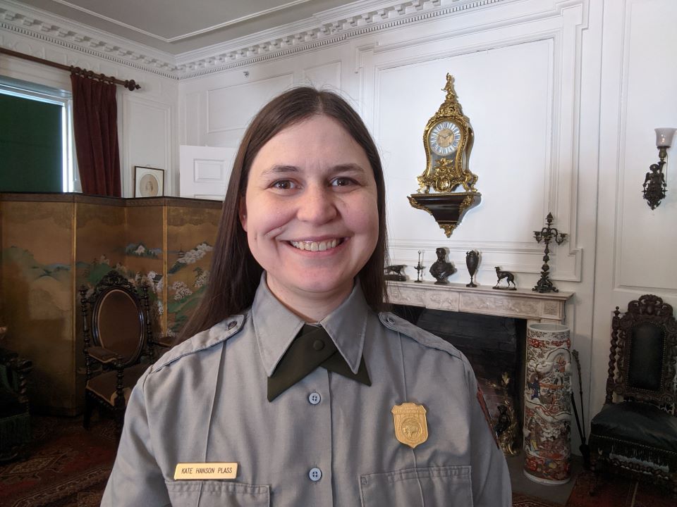 Library at Longfellow House Woman in NPS uniform standing in front of mantle in Victorian furnished room