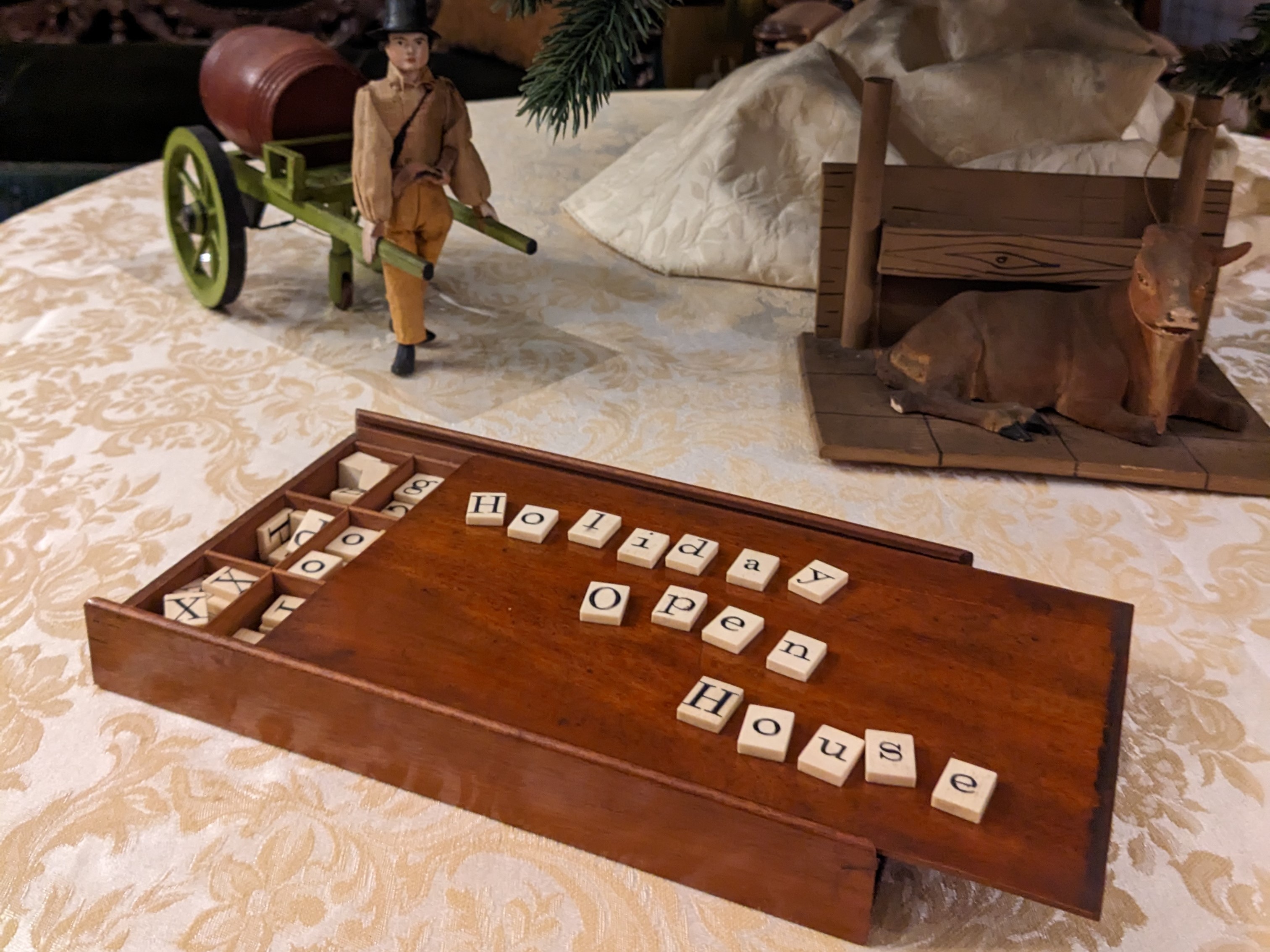 Holiday Open House 19th century game board showing "Holiday open house" in letter tiles with toys and tree in background