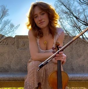 Annica McDougall seated outside holding a violin