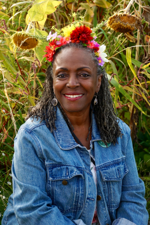 Ekua Holmes seated among sunflowers wearing a flower crown.