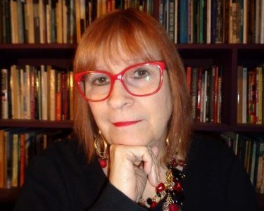 Headshot of Gloria Mindock in front of bookcase
