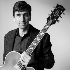 Black and white photo of a man holding a guitar
