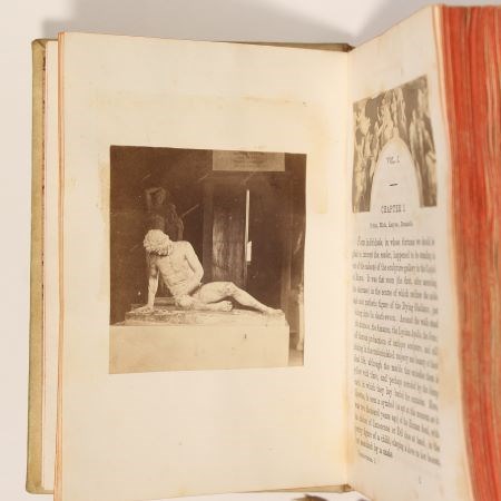 19th century book opened to show a photograph of a marble statue, with text on the facing page.