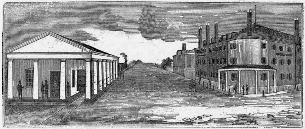 Both sides of Lowell’s Dutton street are visible. On the right is the Merrimack House, a tall four story building with many chimneys, small windows and columns and an awning at the corner. The railroad depot is across the street.