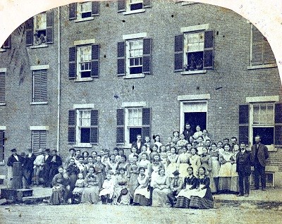 A posed photograph of workers outside of a boardinghouse