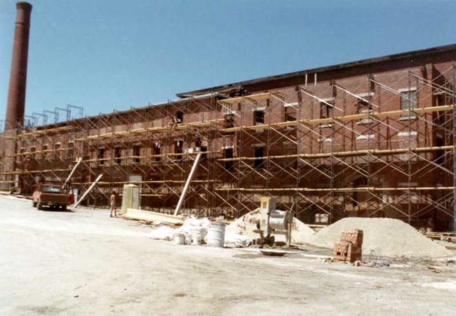A boarding house during renovation. Scaffolding lines the exterior of the building over multiple floors.