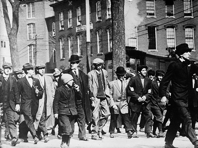 Workers lock arms in solidarity, marching down the street.