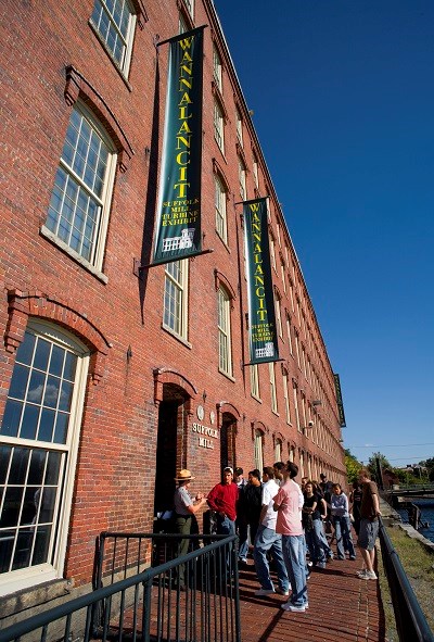 A group of visitors enter the five story brick Suffolk Mills