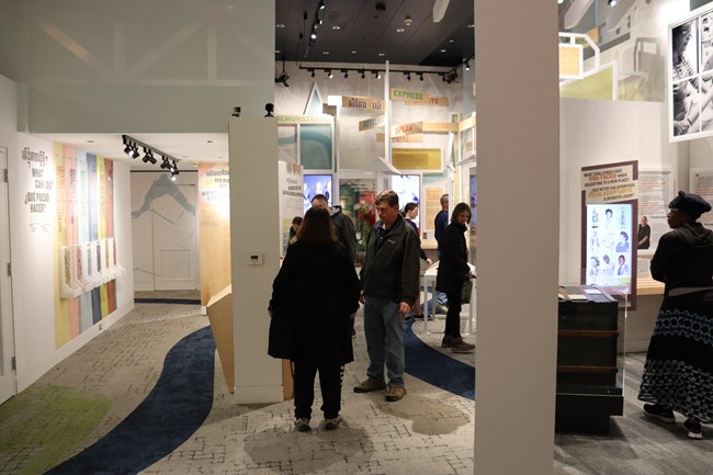 A group of people stand in a museum exhibit reading text on the walls