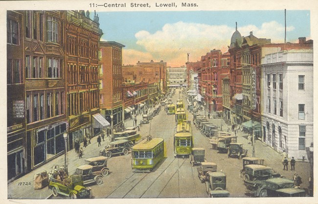 Several yellow trolleys travverse a downtown main road, surrounded by brick buildings