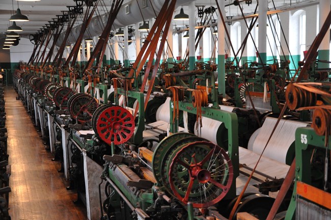A view of the Boott Cotton Mills Museum weave room showing rows of historic weaving machines