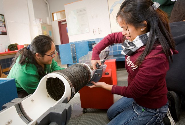 Two young girls build a model canal as part of the tsongas program, turning nuts and bolts