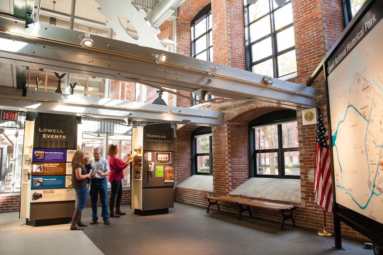 A small group of people explore brochures and information at a visitor center.