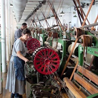 Weavers working on looms in the weave room