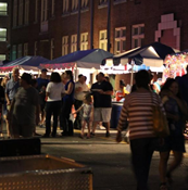 A crowded street at night full of people and tents