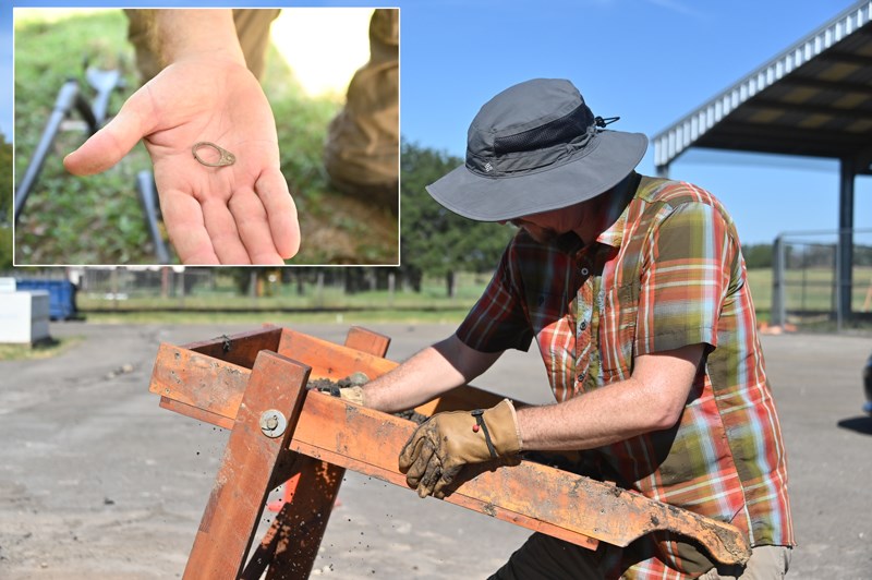 A man examines soil in a wooden box. An inset photo shows a hand holding a pop can tab.