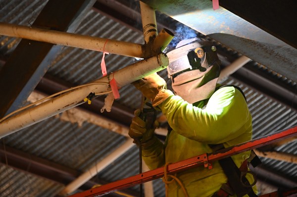 A bright glow illuminates a welder in helmet and gloves.