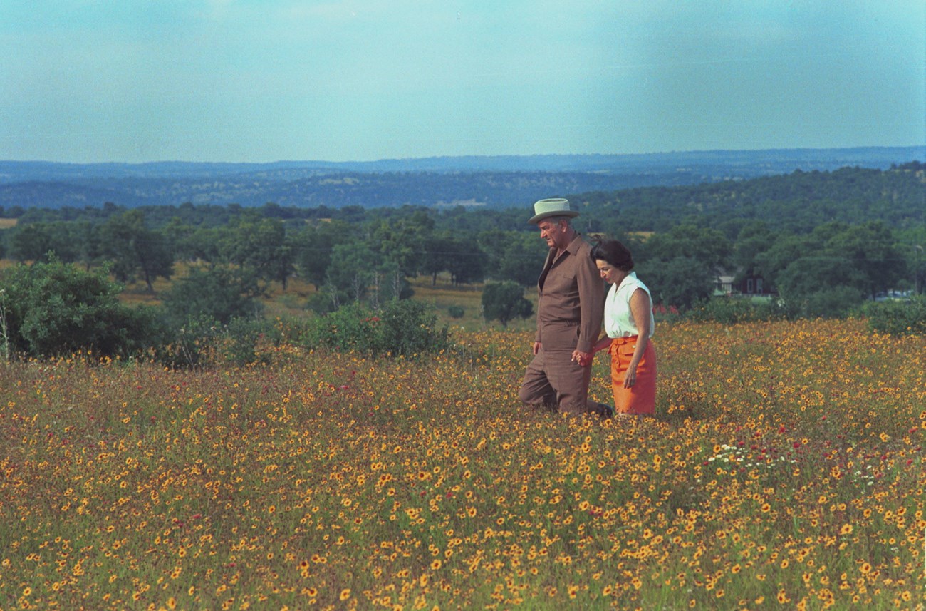 President Lyndon B. Johnson and Lady Bird Johnson walking through a field of flowers