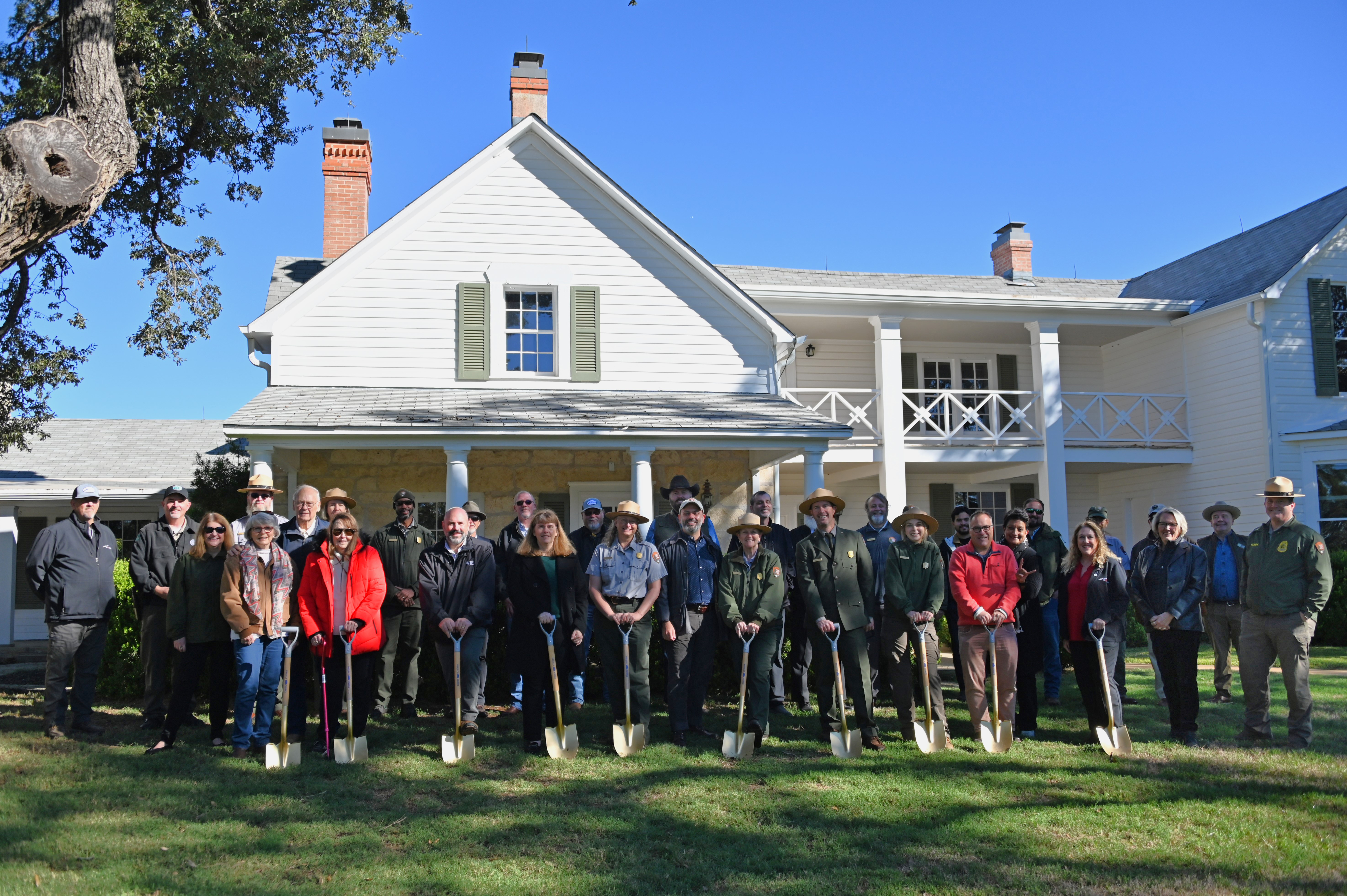 Groundbreaking NPS Photo by Douglas Smith A large group of people, some holding gold shovels, stand in front of a big, two-story, white frame house.