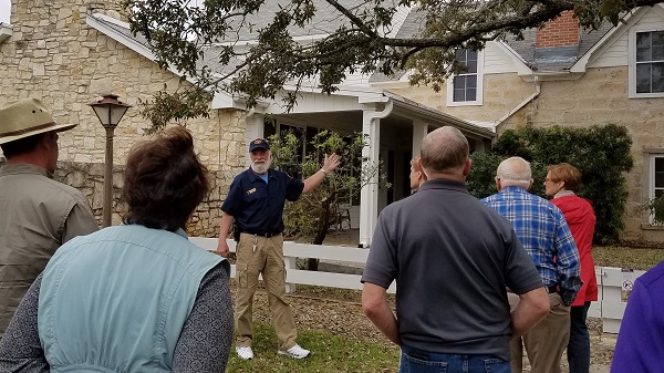 A park volunteer speaks to visitors outside the Texas White House.