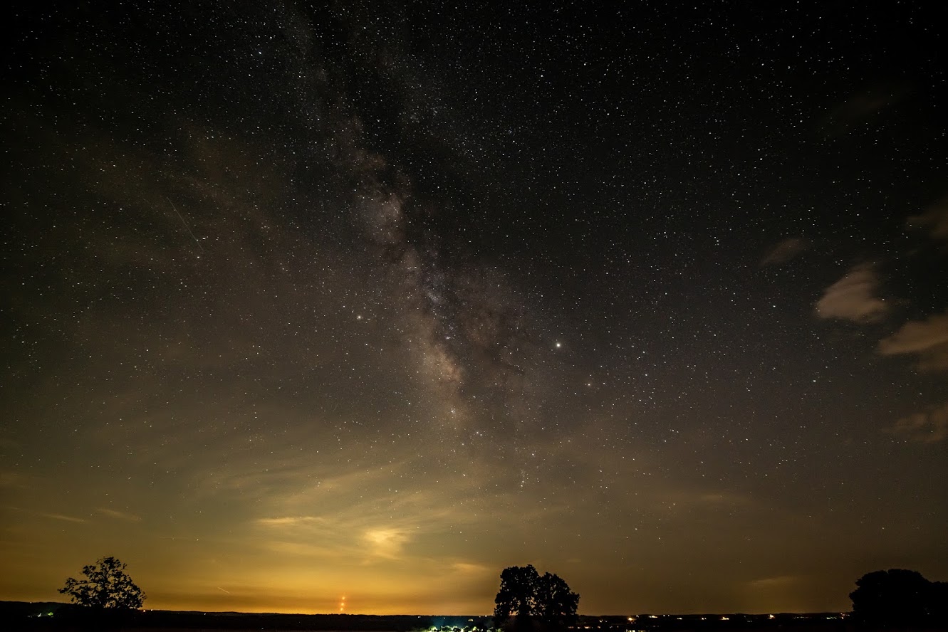 Millions of stars light up the sky over the dark silhouette of ranch pastures
