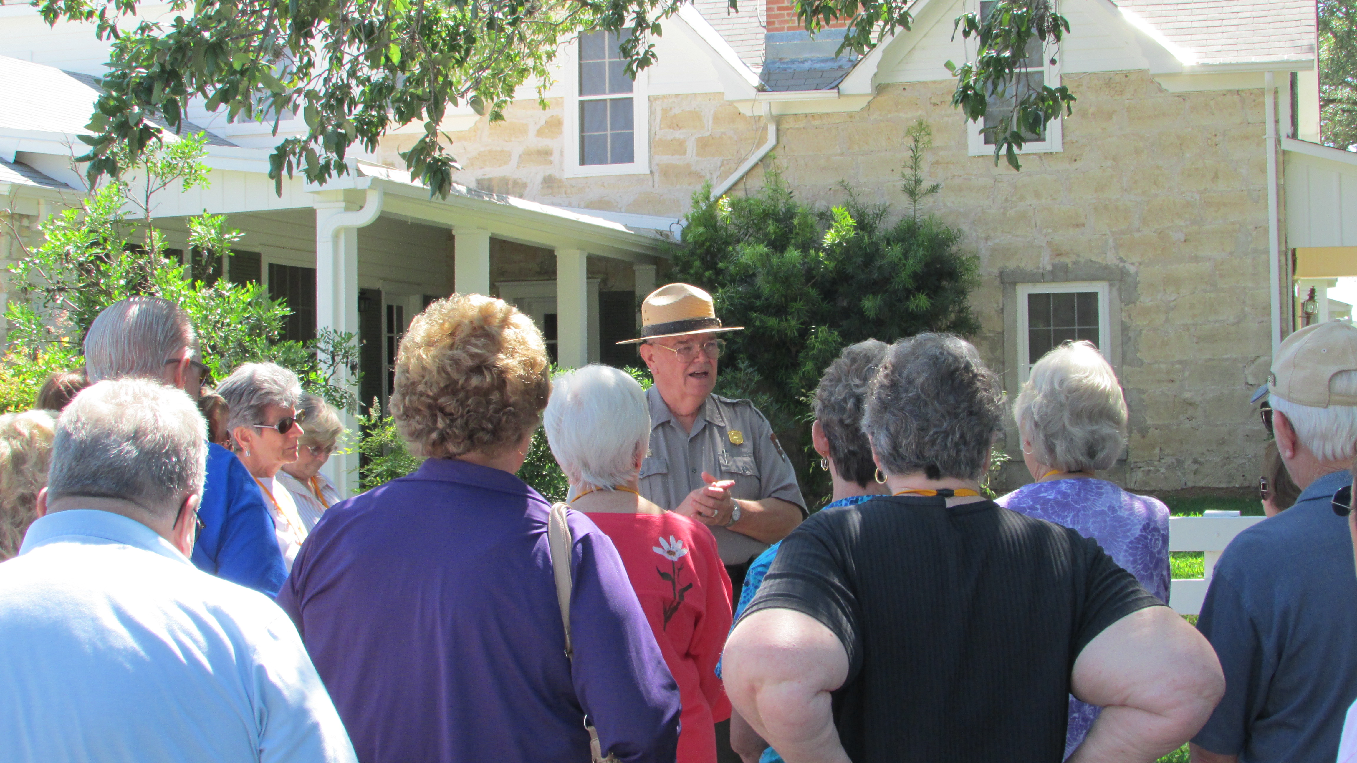 A ranger speaks to a large group of people in front of the Texas White House.