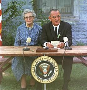 President Johnson sits besides Ms. Kate Deadrich Loney at the signing of the Elementary and Secondary Education Act.